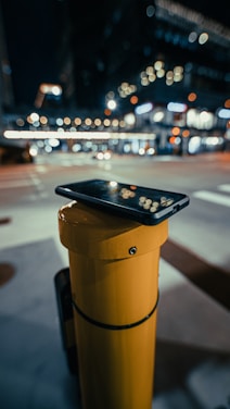 Technician repairing a smartphone late at night with city lights in the background.