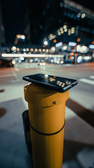A sleek, modern smartphone resting on a city bench with blurred urban lights in the background.