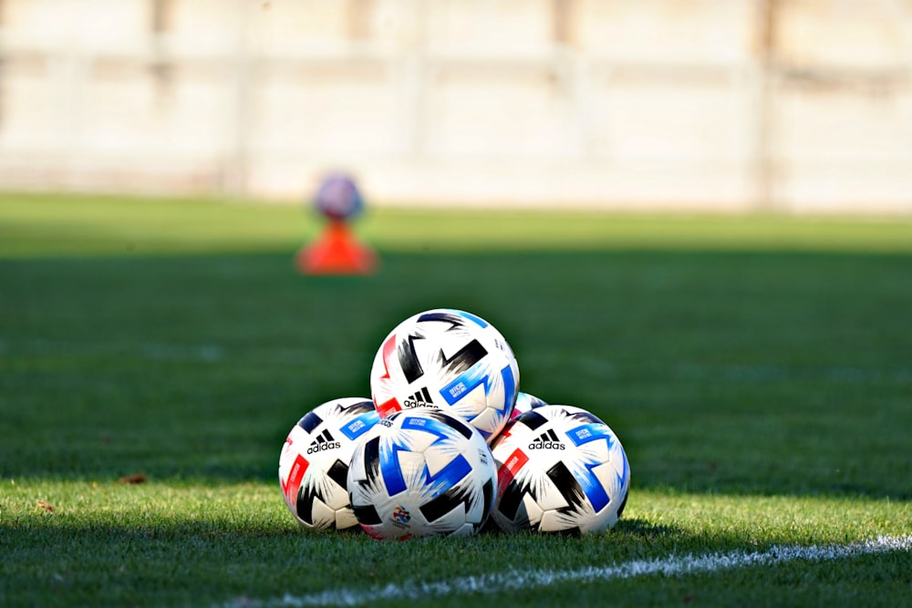 Balón de fútbol blanco, azul y rojo en el campo de hierba verde durante el día