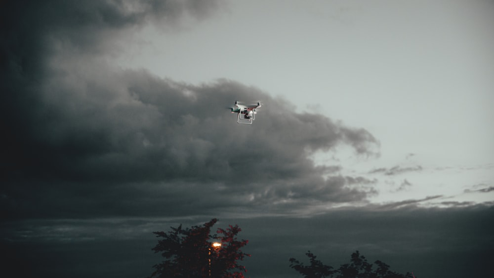 Drone bianco e rosso che vola sopra gli alberi