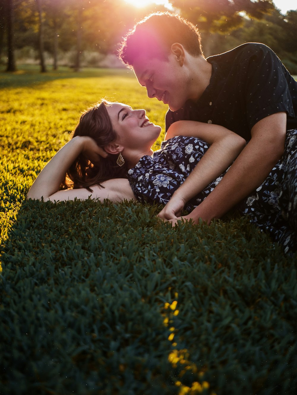 hombre y mujer tumbados en el campo de hierba verde durante el día