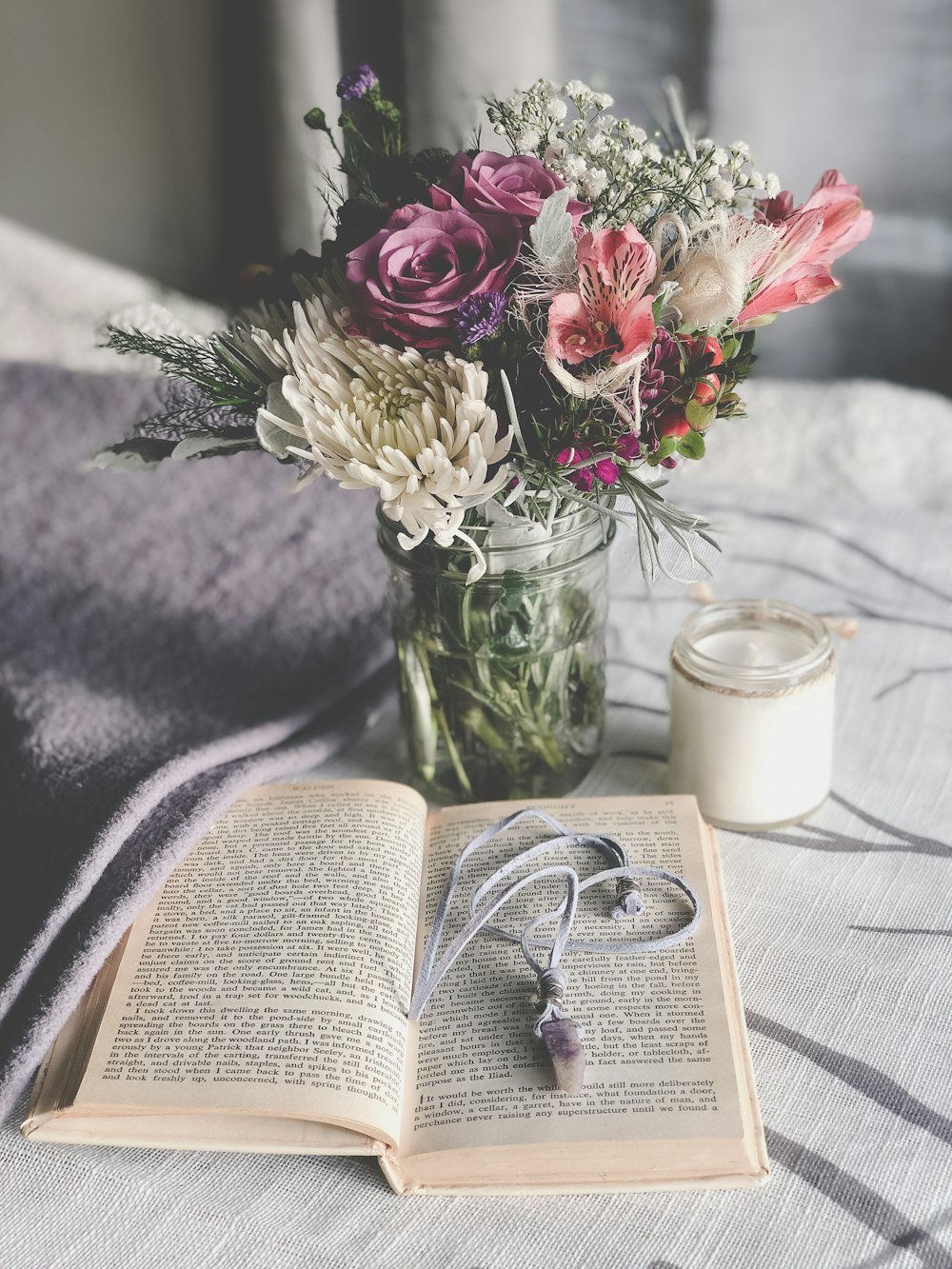 pink and white roses in clear glass vase beside white ceramic mug on white book page