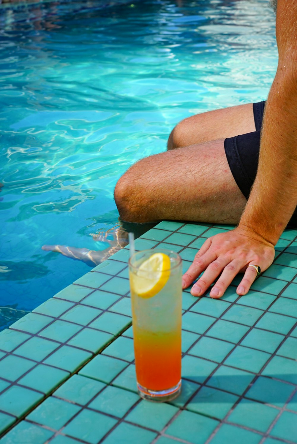 man in black shorts holding clear drinking glass with yellow liquid