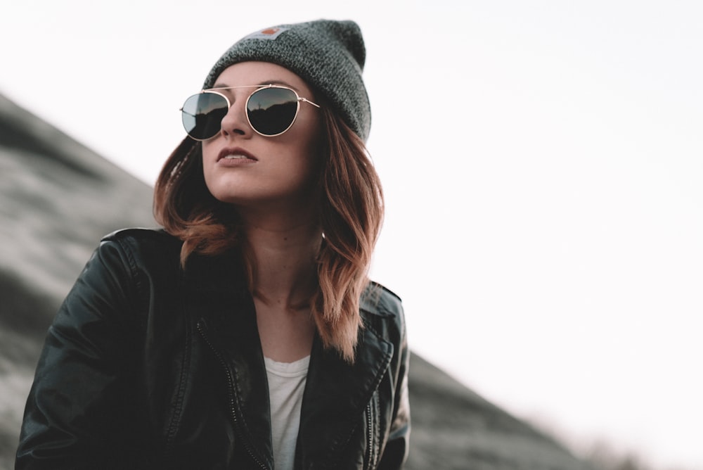 woman in black jacket wearing black sunglasses and gray knit cap