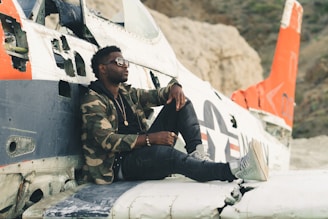 man in black and brown camouflage uniform sitting on white plane