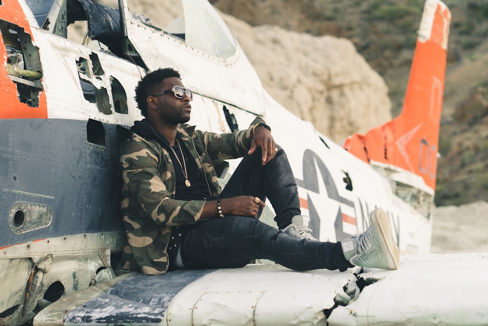 man in black and brown camouflage uniform sitting on white plane