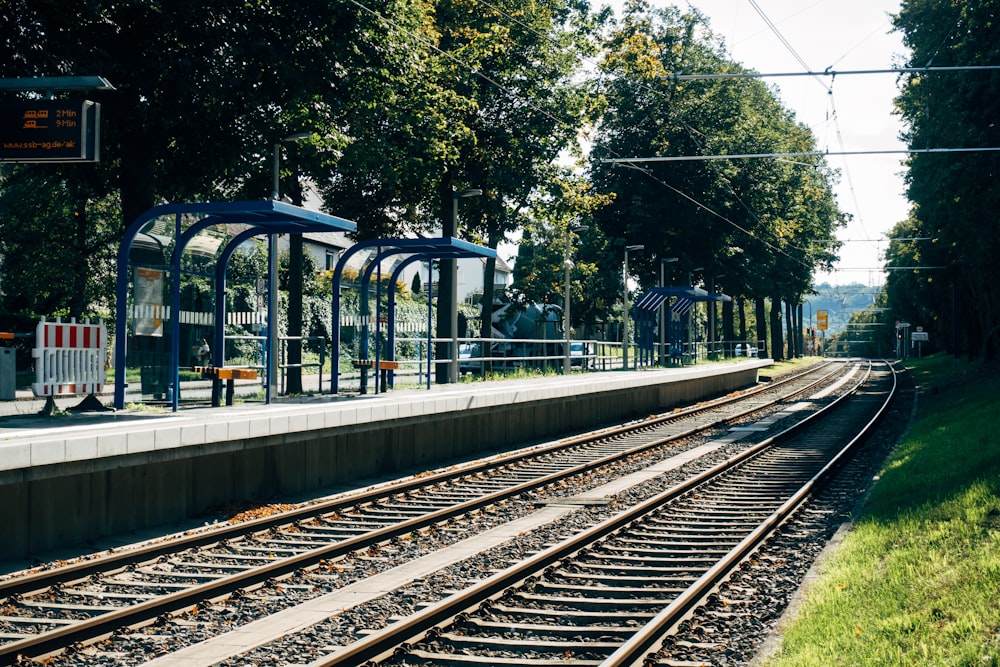 train rail near green trees during daytime