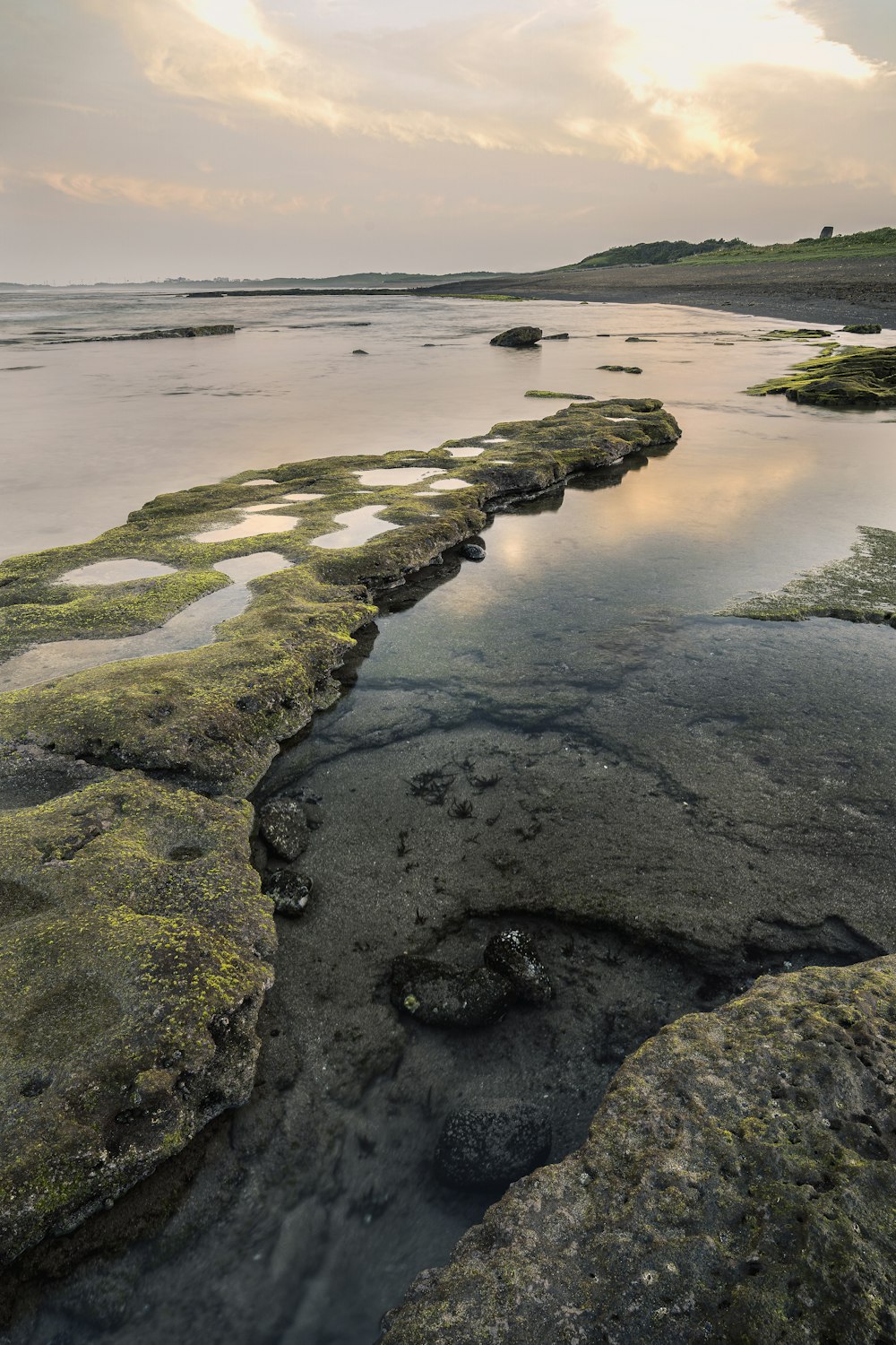 formación de rocas marrones y verdes en el cuerpo de agua durante el día