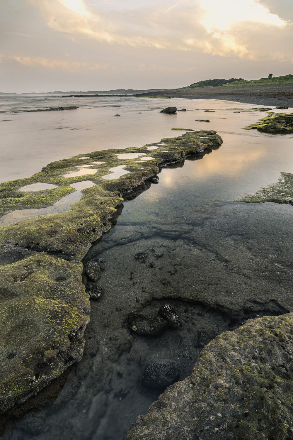 brown and green rock formation on body of water during daytime