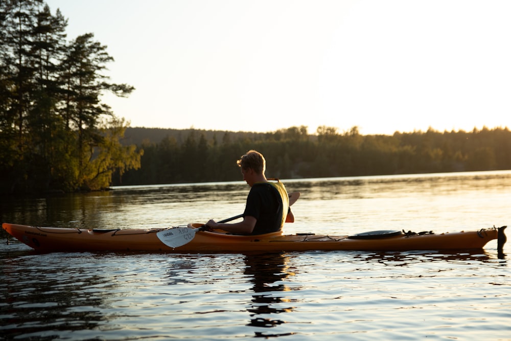 woman in yellow shirt riding on brown kayak on lake during daytime