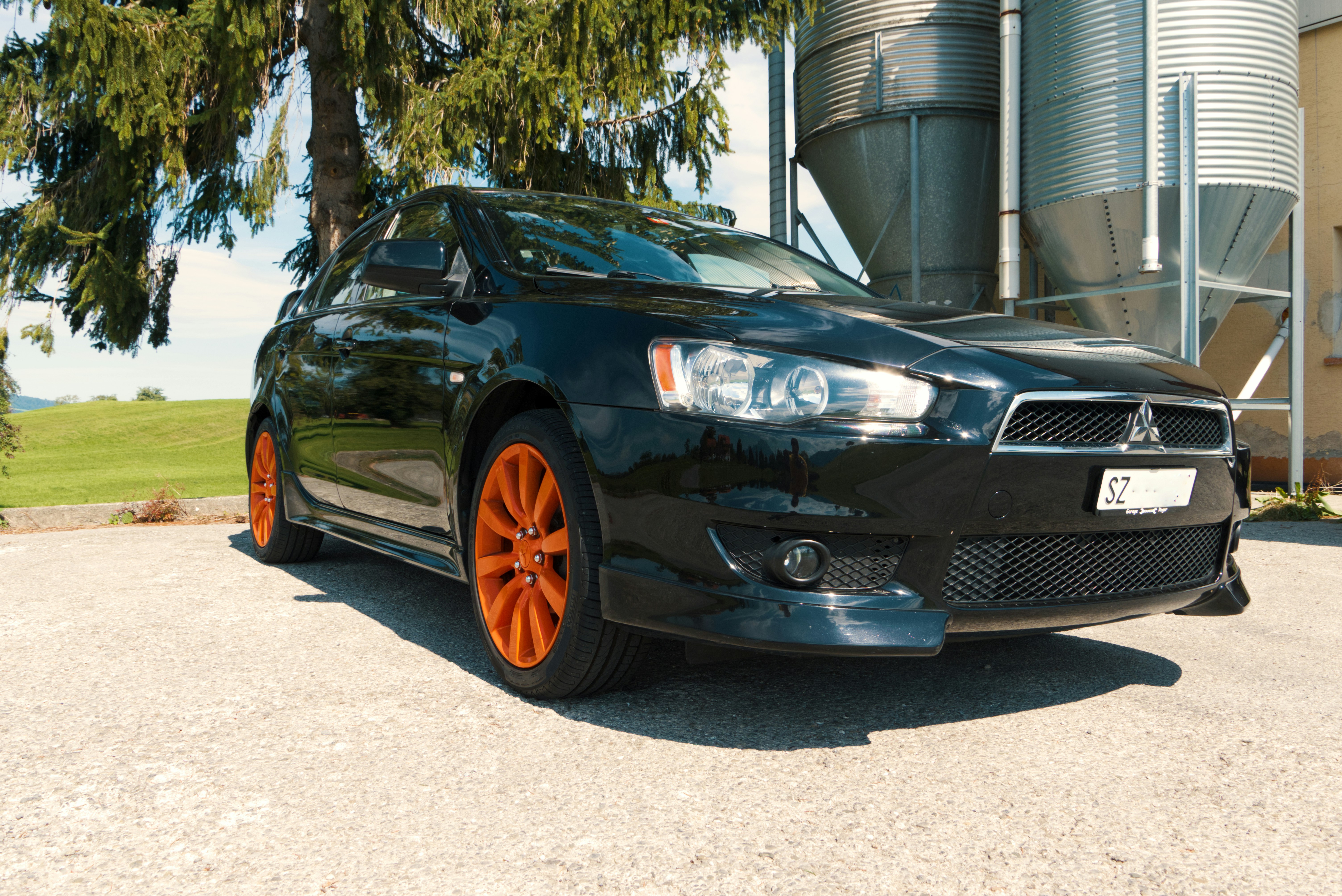 black bmw x 6 parked near gray building during daytime mitsubishi teams background