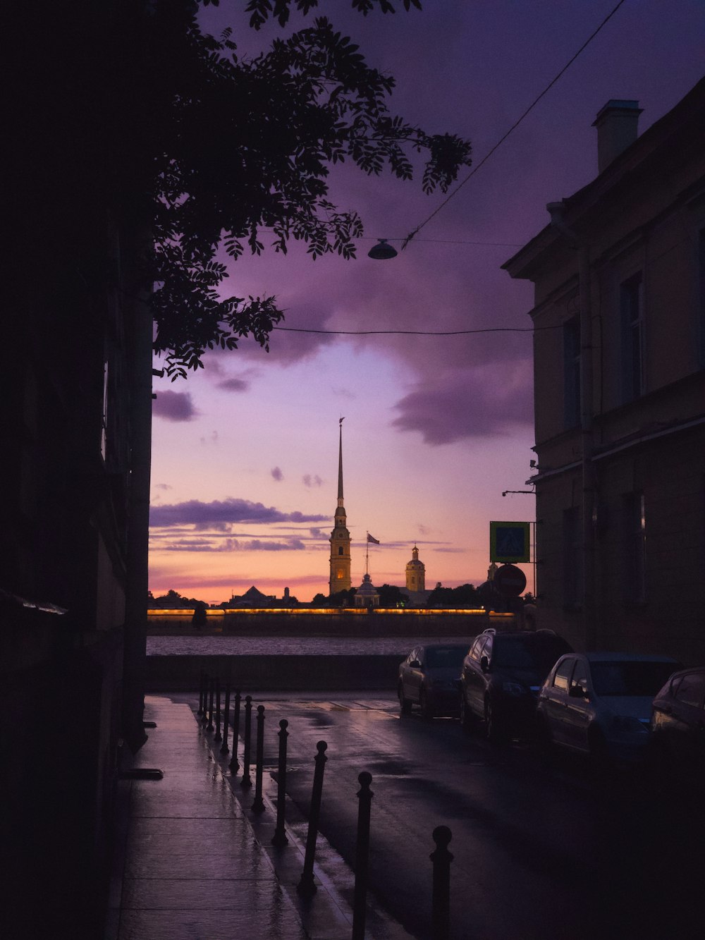 cars parked on sidewalk near building during sunset