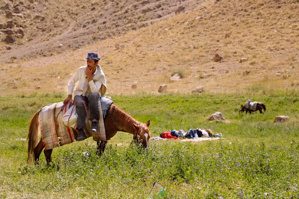 man in brown pants and brown leather boots sitting on green grass field during daytime