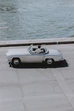 A stylish convertible cruising along a scenic European coastal road.