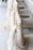 Several chairs are adorned with sheer, flowing fabric in soft beige and cream hues, elegantly draped over the backs. The arrangement suggests a setting for a formal event, possibly a wedding or banquet. The fabric adds a touch of sophistication and luxury to the seating arrangement.