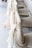 Several chairs are adorned with sheer, flowing fabric in soft beige and cream hues, elegantly draped over the backs. The arrangement suggests a setting for a formal event, possibly a wedding or banquet. The fabric adds a touch of sophistication and luxury to the seating arrangement.