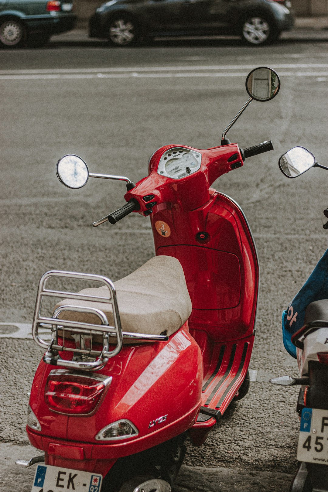 red motor scooter parked on gray asphalt road during daytime