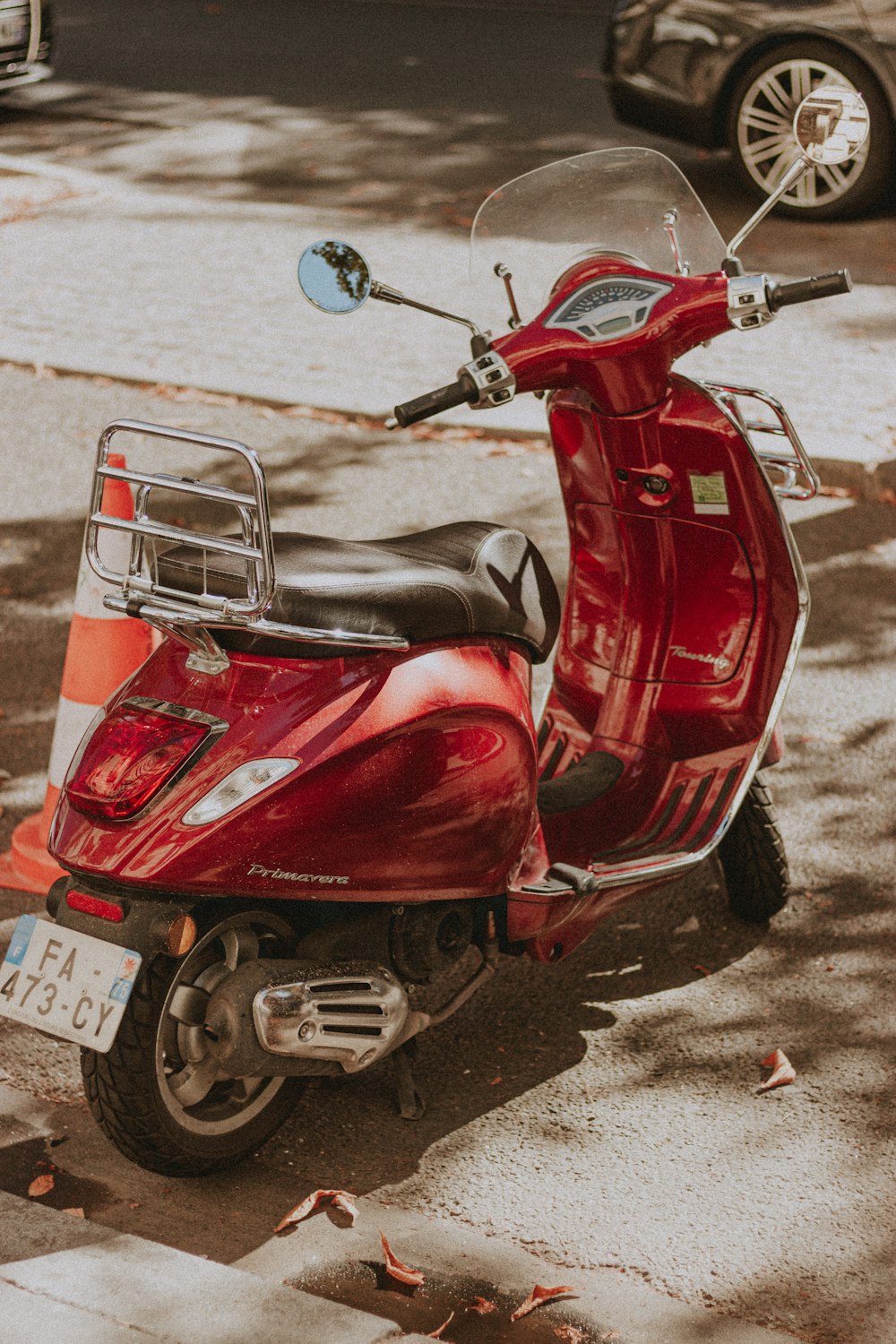 red and black motor scooter parked on gray concrete pavement during daytime