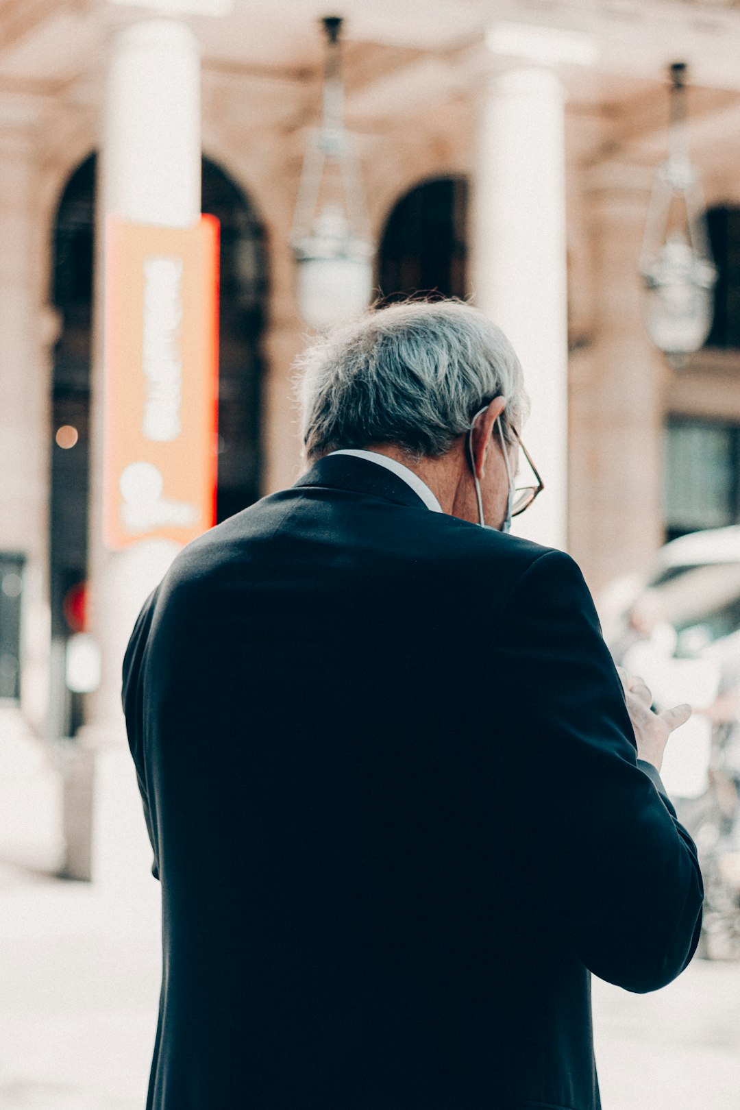 man in black suit jacket standing near building during daytime