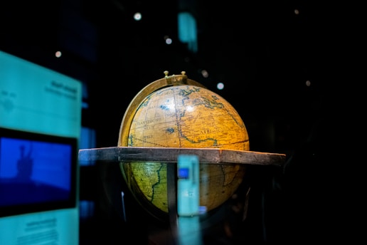 A vintage globe resting beside an open ancient manuscript, bathed in warm sunlight.