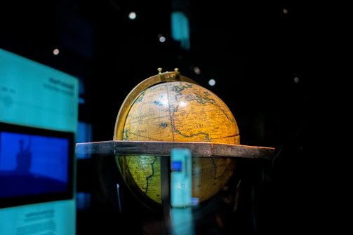 A sleek black and gold globe sculpture illuminated softly against a dark background.