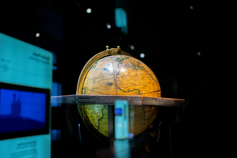 A sleek black and gold globe sculpture illuminated softly against a dark background.