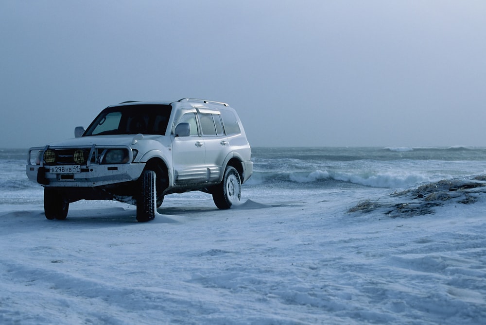 suv branco na costa do mar durante o dia