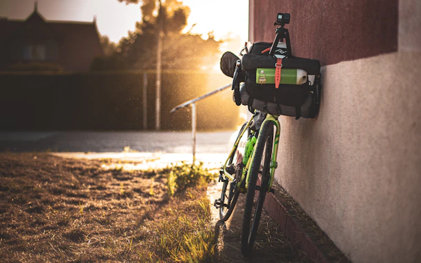 A vibrant outdoor scene showing a cyclist mounting a camera on a bike handlebar against a mountain backdrop.