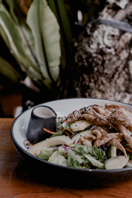 Grilled chicken salad with colorful vegetables and a light dressing served in a ceramic bowl