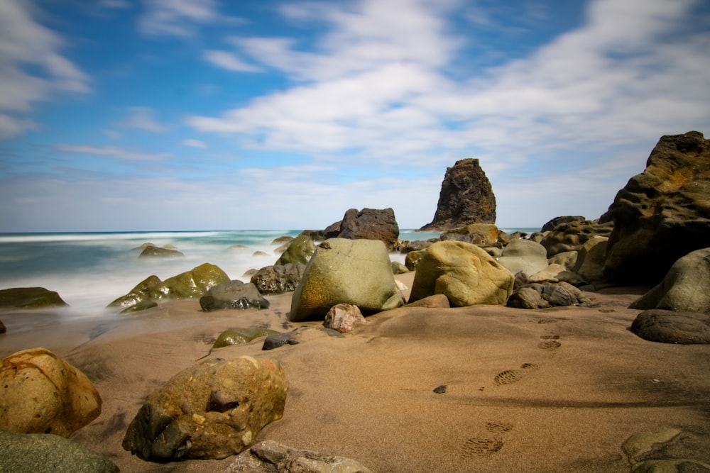 brown rocks on seashore under blue sky during daytime