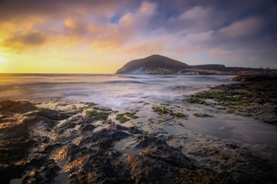 ocean waves crashing on shore during sunset