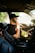 man in black t-shirt and brown hat driving car
