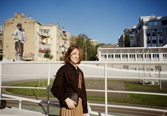 woman in black jacket standing on the sidewalk during daytime