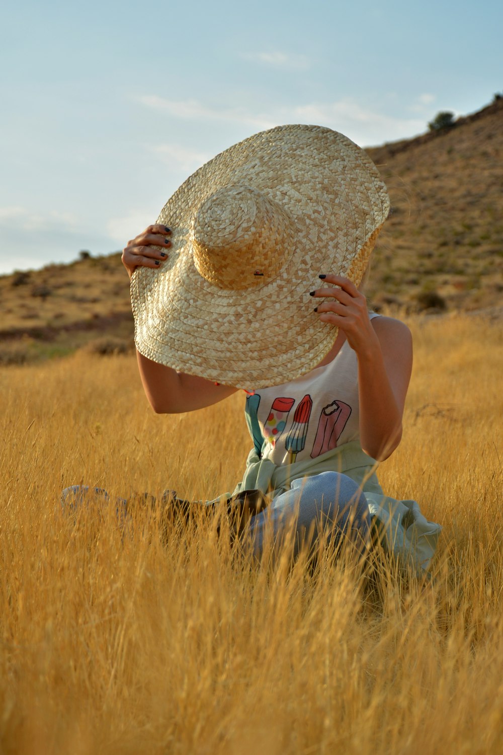 woman in white and red dress wearing brown sun hat standing on brown grass field during