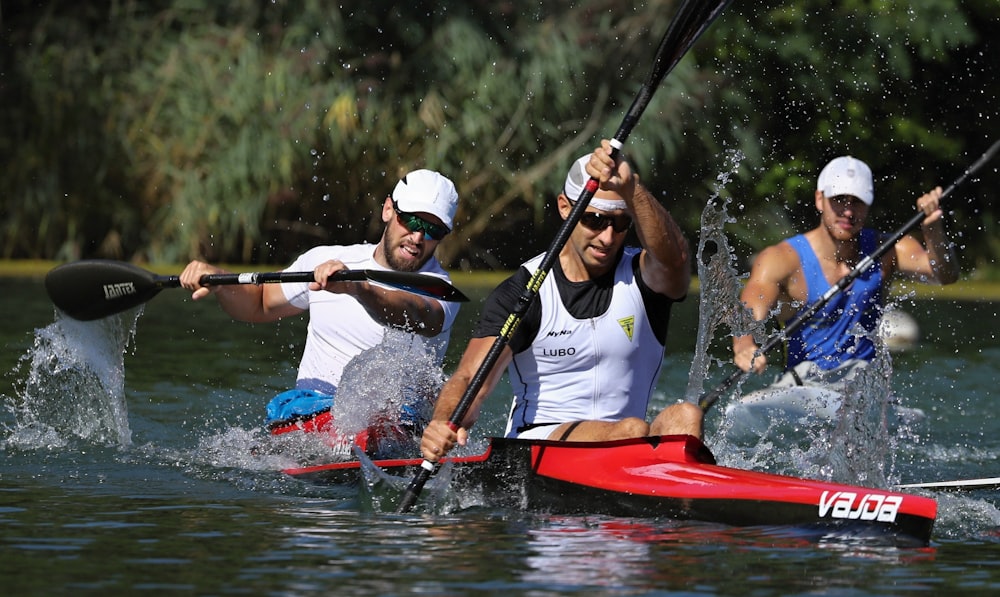 man in white shirt and red vest riding red kayak