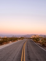 A winding desert road disappearing into the glowing horizon at dusk.