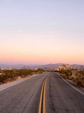A winding desert road disappearing into the glowing horizon at dusk.