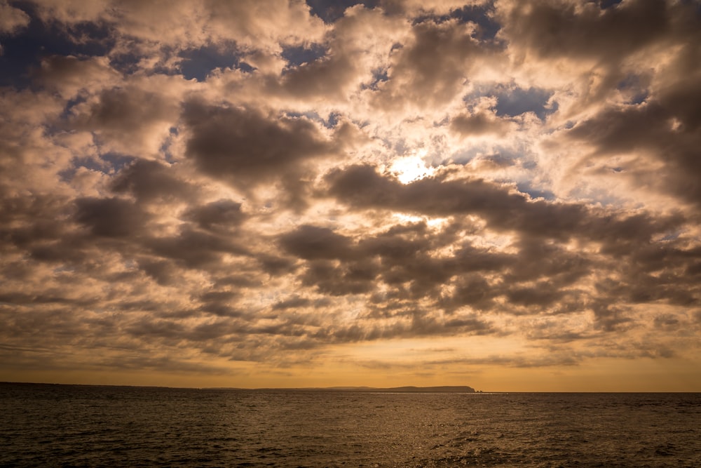 body of water under cloudy sky during sunset