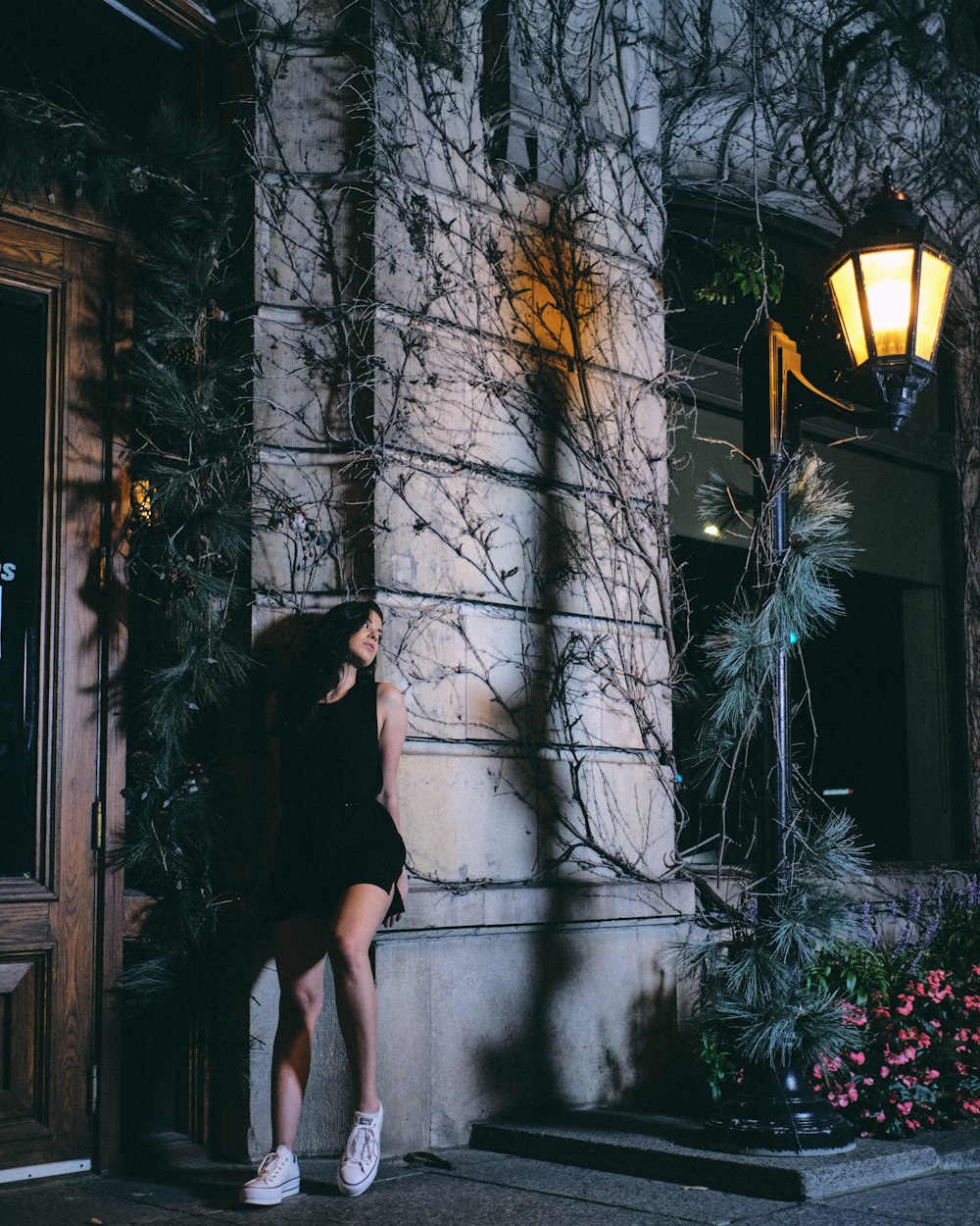 woman in black dress standing beside window