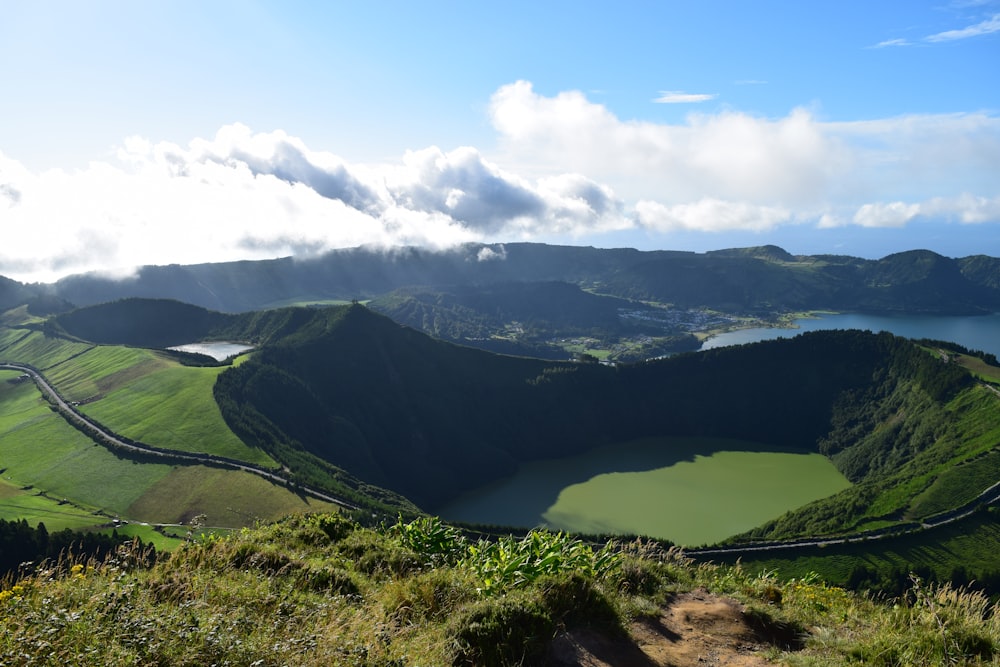 昼間の白い雲の下の緑の山々