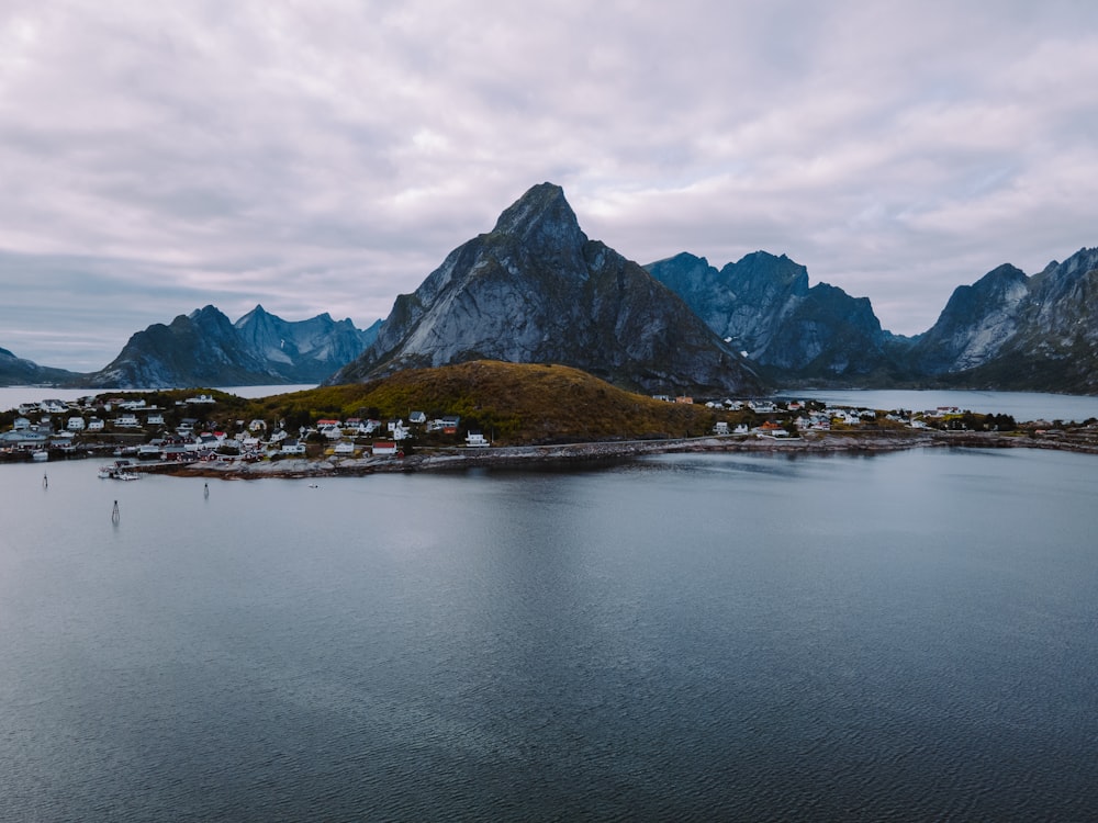 body of water near mountain under cloudy sky during daytime