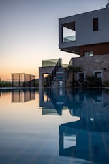 Modern luxury villa exterior with minimalist architectural lines and subtle gold accents at sunset.