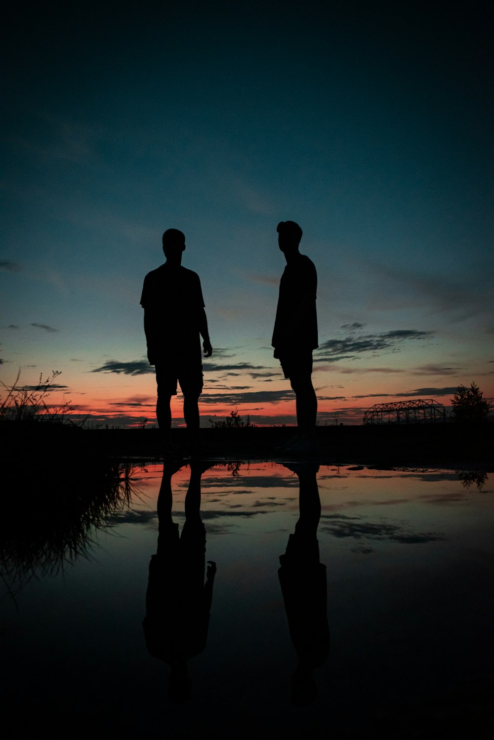 silhouette of couple standing on seashore during sunset