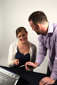 Close-up of a consultant discussing AI strategy with a client over a tablet, set against a silver-toned backdrop.