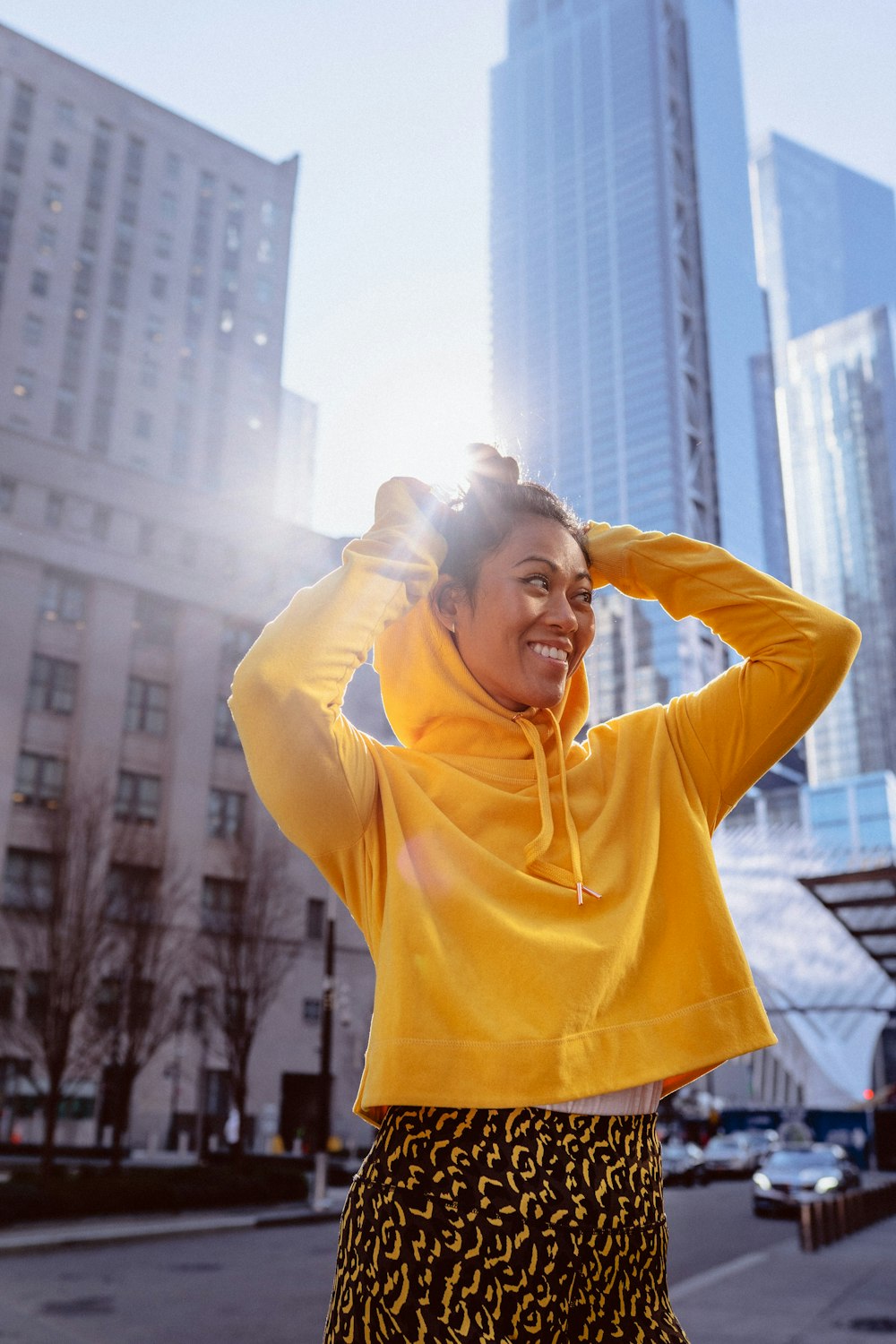 woman in yellow hoodie standing on the city during daytime