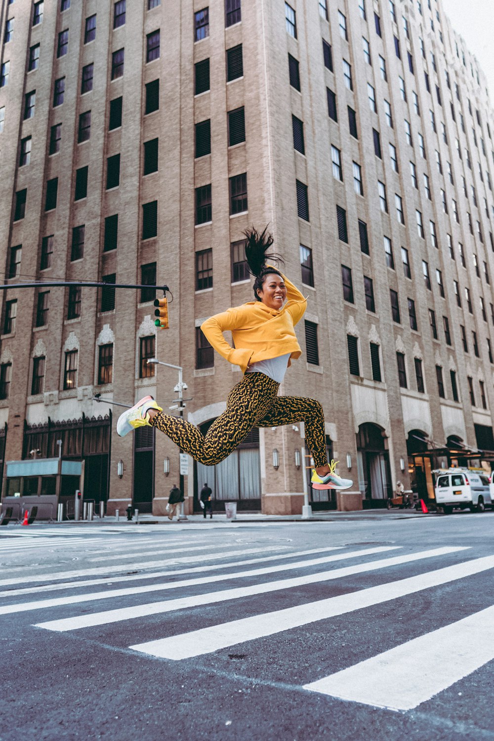 woman in white long sleeve shirt and black pants jumping on street during daytime
