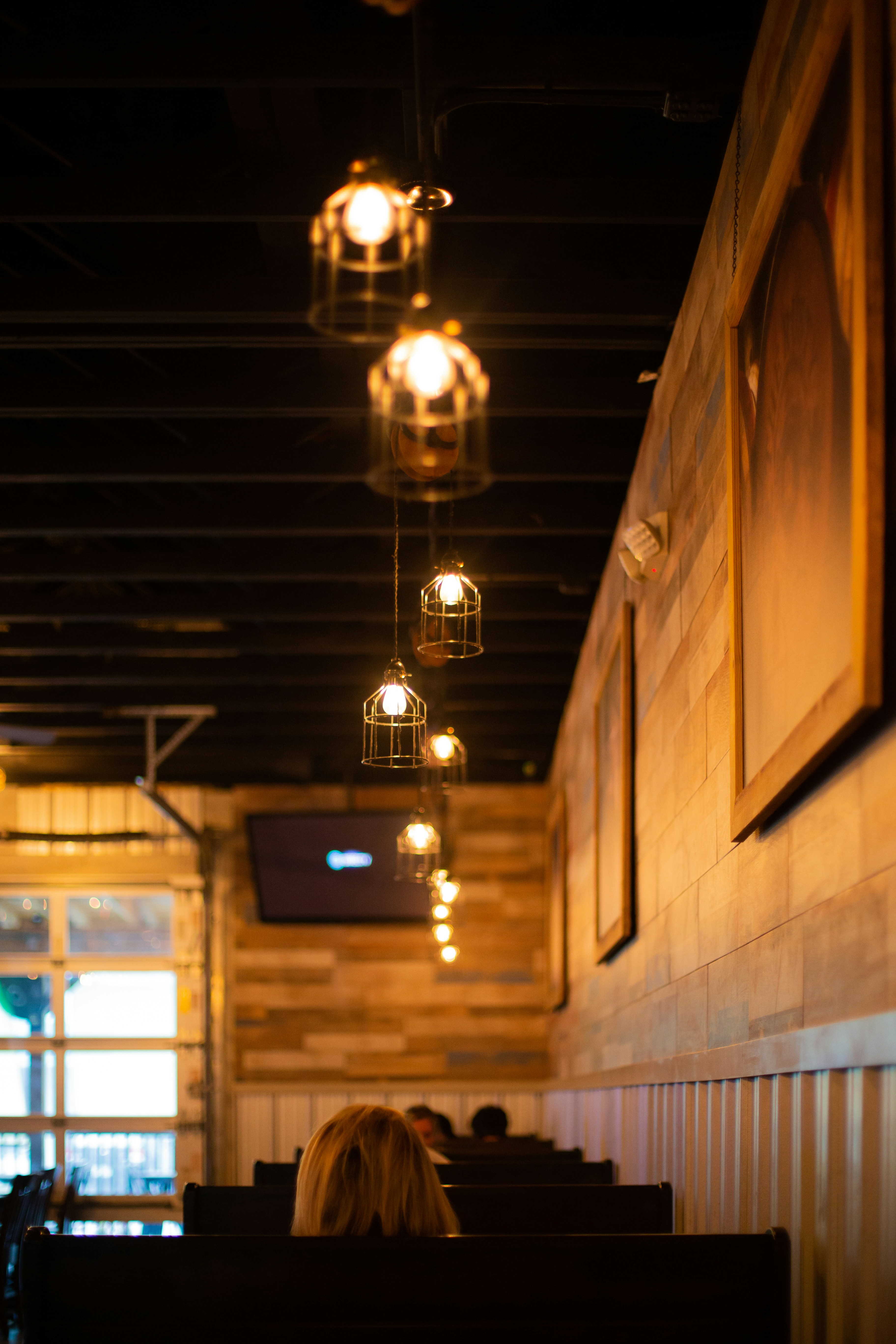 Bright warm restaurant interior with pendant lights, wooden tables, and inviting ambiance
