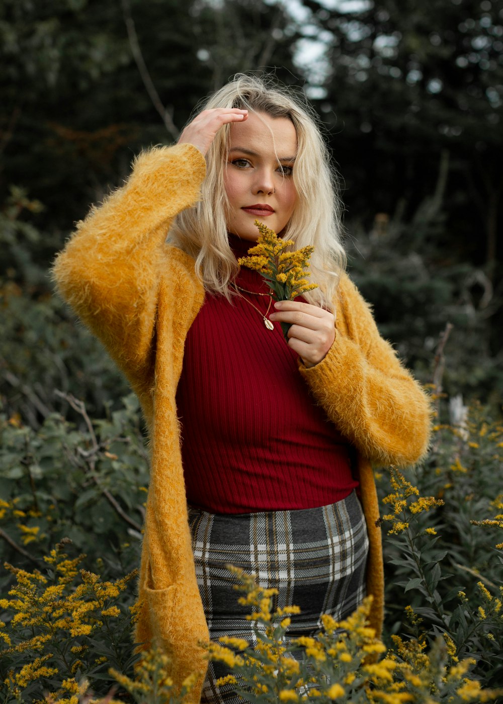 woman in red shirt and brown coat standing near brown tree during daytime