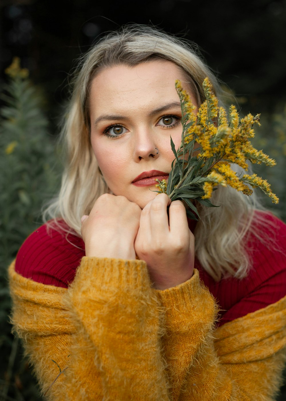 woman in red long sleeve shirt holding yellow flowers