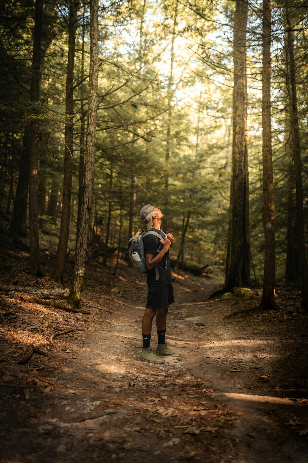 man in black jacket and black pants standing in the middle of forest during daytime